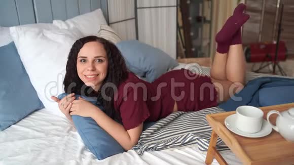穿着睡衣睡在床上的漂亮年轻女人迷人的女性躺着看镜头的肖像视频的预览图