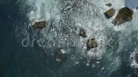 鸟瞰蓝色海洋中岩石上的波浪视频的预览图
