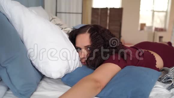 年轻漂亮的女人穿着睡衣躺在床上成年女士在睡觉时休息和看摄像机视频的预览图