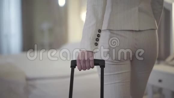 无法辨认的高加索女人带着手提箱在酒店房间里接近床优雅的白衣少女视频的预览图