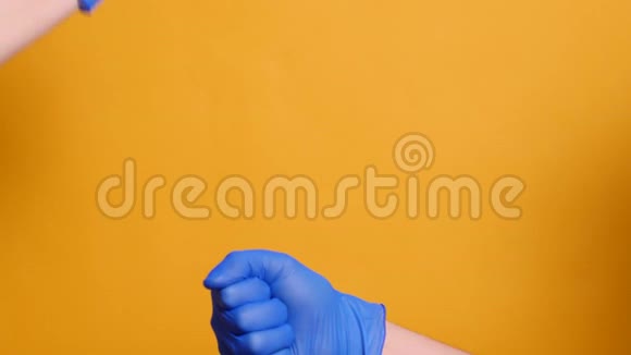 两人戴着黄色背景的蓝色医用手套握手视频的预览图