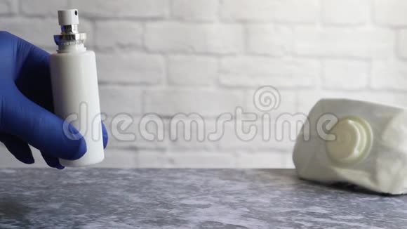 一只戴蓝色手套的手放在桌子上一个带有防护面罩的防腐剂的气溶胶罐预防细菌流行视频的预览图