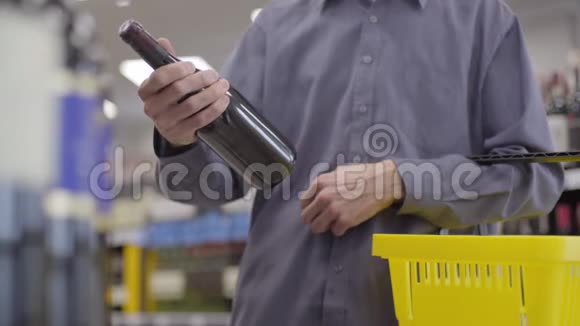 男性白种人手里拿着一瓶红酒在酒精超市不知名的成年人把饮料放进黄色视频的预览图