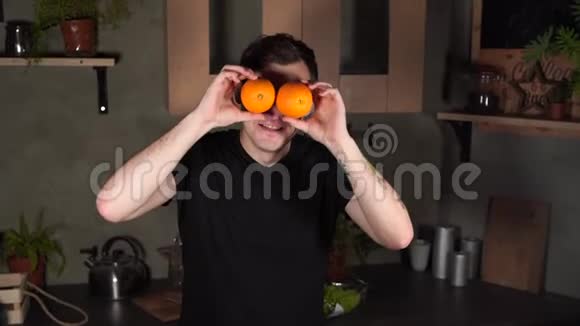 年轻人把脸藏在厨房的水果后面成年帅哥在镜头前调情和看橘子视频的预览图