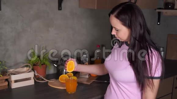 一个女孩在厨房里挤压一个橘子得到新鲜的橙汁特写女人挤橙汁视频的预览图