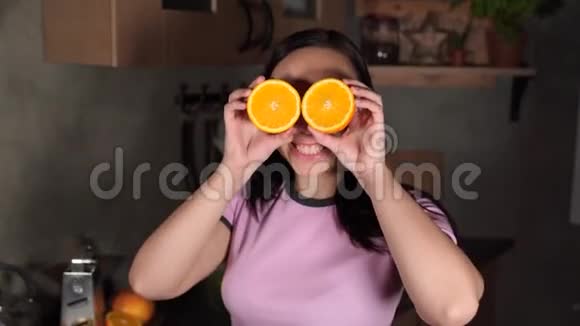 年轻女子把脸藏在厨房的水果后面成年女士在镜头前调情看着橘子视频的预览图