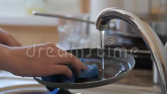一个女人的特写镜头她在一股水流下的厨房里洗碗视频的预览图