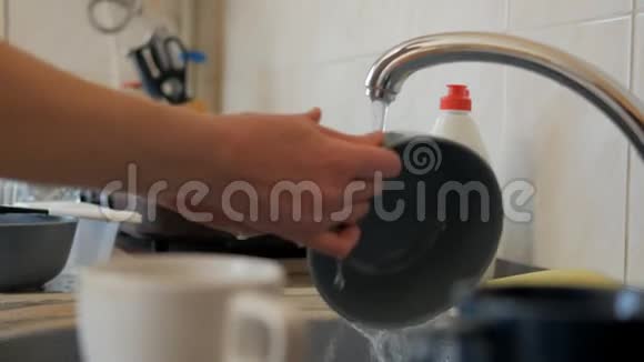 一个女人的特写镜头她在一股水流下的厨房里洗碗视频的预览图