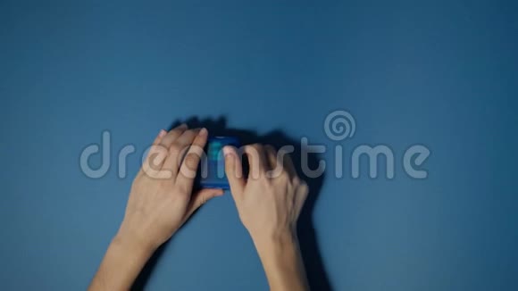 双手打开装有药丸和维生素的蓝色背景的塑料盒子视频的预览图