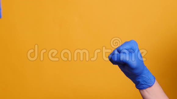 两人戴着黄色背景的蓝色医用手套握手视频的预览图