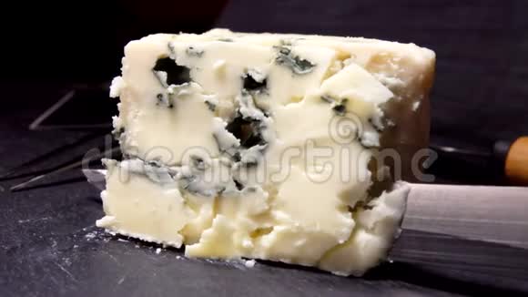 刀从黑色的石头表面举起一块蓝金奶酪视频的预览图