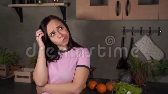 困惑的年轻女人在厨房挠头肖像女性在思考什么时挠头视频的预览图