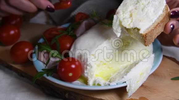 女人的手在面包上放一片西红柿在一片新鲜的马拉上意大利三明治准备吃我做的食物视频的预览图
