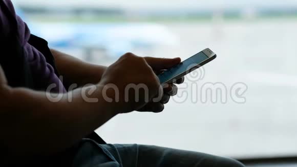 人在机场候机楼使用手机等待登机视频的预览图