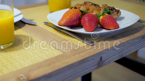 新鲜草莓牛角面包和橙汁放在木桌上在家吃早餐平静和放松的早晨视频的预览图