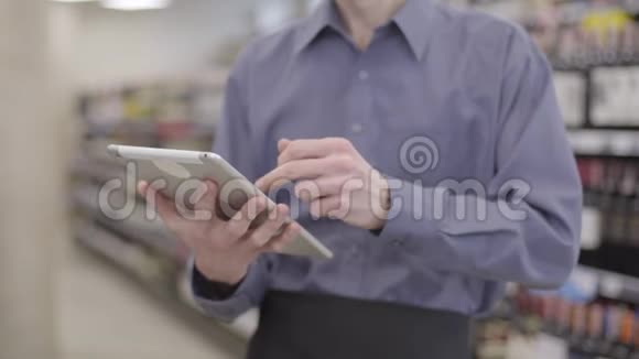 无法辨认的成年白人男子使用平板电脑的背景下模糊的货架与酒精在超市男性视频的预览图