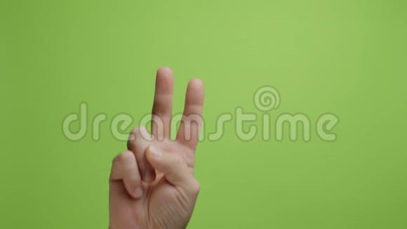 手是符号绿色背景下男子手举和平胜利手势视频的预览图