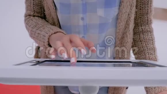 女性手使用触摸屏显示地板站立白色平板电脑亭视频的预览图