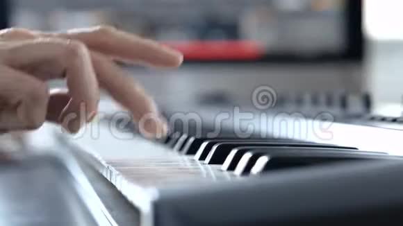 录音室的年轻人用右手合上钢琴键盘上的手学习如何玩视频的预览图
