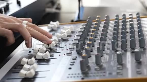 录音室的年轻人使用混合控制台关闭双手专业录音视频的预览图