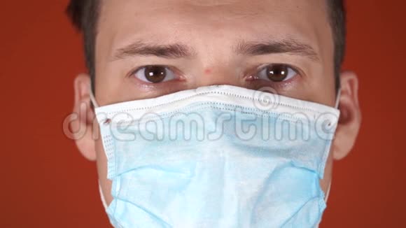 橙色背景上脸上戴着医疗面具的男人冠状病毒的流行视频的预览图