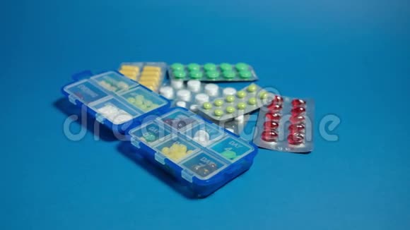 药丸盒和药片在蓝色背景上视频的预览图
