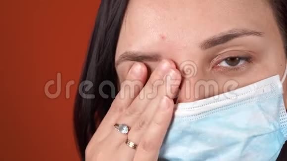 橙色背景下脸上戴着医疗面具的女人冠状病毒的流行视频的预览图