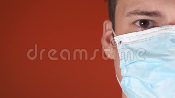 橙色背景上脸上戴着医疗面具的男人冠状病毒的流行视频的预览图