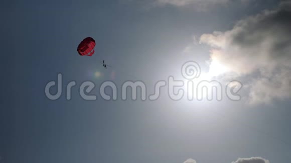 游客在晴朗的蓝天上乘红色降落伞视频的预览图