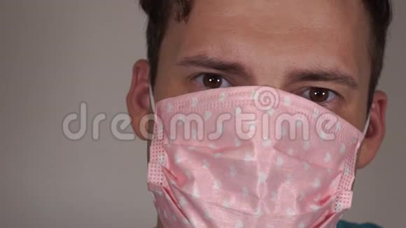 在灰色背景下脸上戴着医疗面具的人冠状病毒的流行视频的预览图
