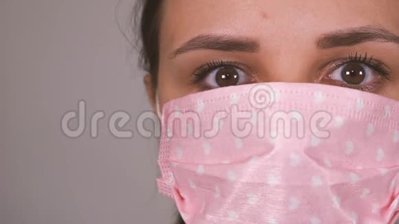 灰色背景下脸上戴着医疗面具的女人冠状病毒的流行视频的预览图