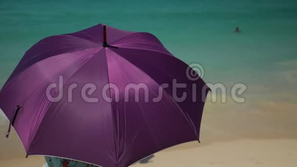 紫伞躲在沙滩上的阳光下视频的预览图