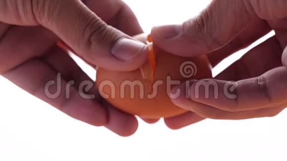 男性手拿着一个破裂的鸡蛋慢动作在白色背景上打破鸡蛋视频的预览图