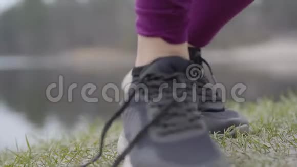 年轻女性双手在运动鞋上系鞋带的特写令人难以辨认的性感女人离开户外锻炼视频的预览图