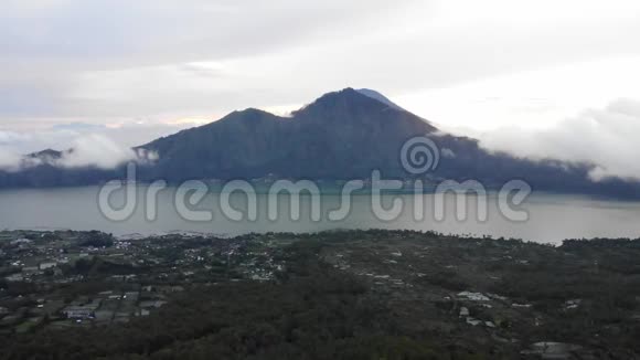 从印度尼西亚巴厘岛巴图尔金塔马尼火山顶部日出时可以看到云和雾的风景视频的预览图