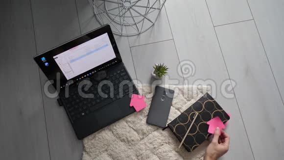 女性手胶贴纸在笔记本上做清单设定目标概念和家庭在线工作顶部视图桌面生产力视频的预览图