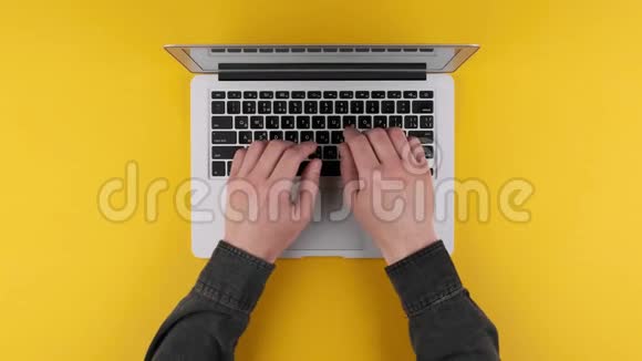 男性手在黄色背景的银色笔记本电脑键盘上打字视频的预览图