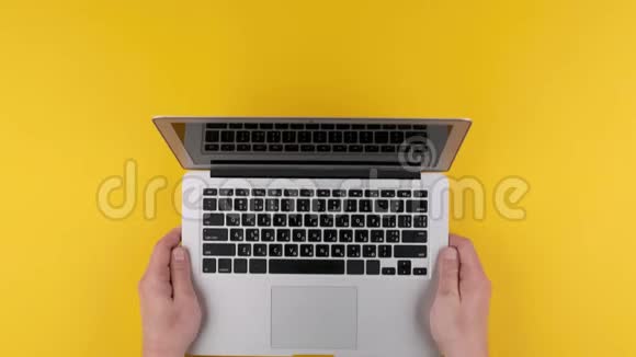 男人把屏幕笔记本电脑放在黄色的桌子上视频的预览图