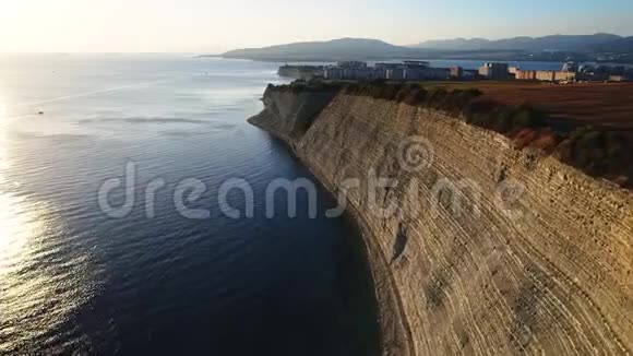 飞越海岸线的海洋与鹅卵石海滩和一个大高岩石悬崖的咸岩石日落时飞翔视频的预览图