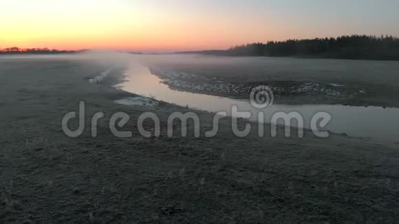 冬天寒冷的早晨雾在河上蔓延这反映了明亮的红色太阳童话视频的预览图