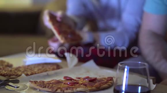 一对男女晚上在客厅的沙发上吃披萨同时在电视上看电影概念视频的预览图