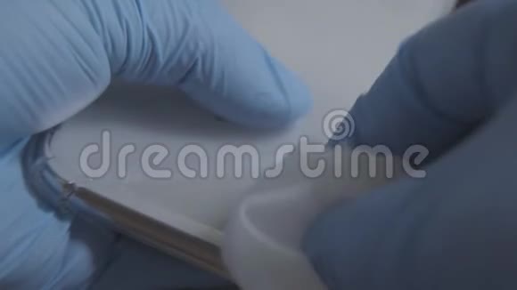 女性手在防护手套中的特写用餐巾纸擦着智能手机无法辨认的女性消毒视频的预览图