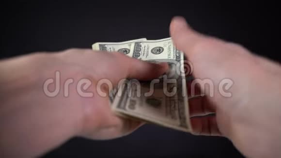 男子在黑色背景下计算美元钞票视频的预览图
