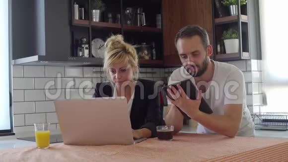 丈夫和妻子在咖啡休息时上网在厨房里得到一个好消息视频的预览图