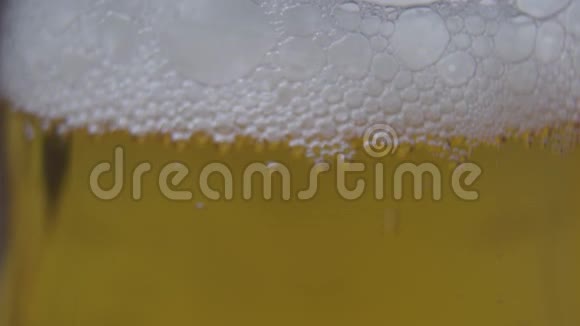 玻璃杯里的泡沫啤酒相机从泡沫向下移动到底部酿造饮料酒精视频的预览图