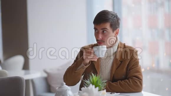 这家伙喝咖啡在咖啡馆里通过社交网络交流一个男人吃早餐用手机说话视频的预览图