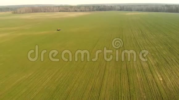 一辆拖拉机在一个绿色的大田上喷洒化学品农业综合企业概念视频的预览图