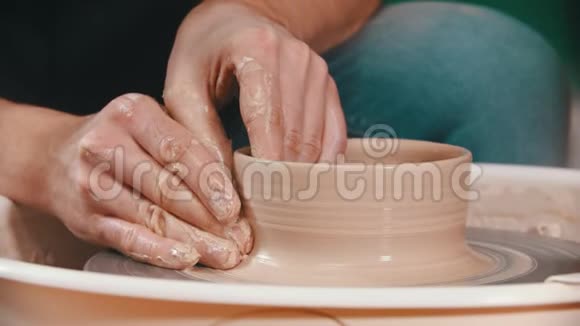 陶艺大师用手在陶工的轮子上举起泥碗的墙壁视频的预览图
