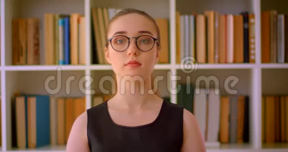 年轻成功的红头发女学生戴着眼镜在室内看着图书馆里的摄像机视频的预览图