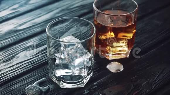 威士忌被倒进一个装有冰块的玻璃杯放在一张黑色的木桌上视频的预览图